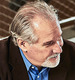 Headshot of John Murray, looking to the right and smiling.