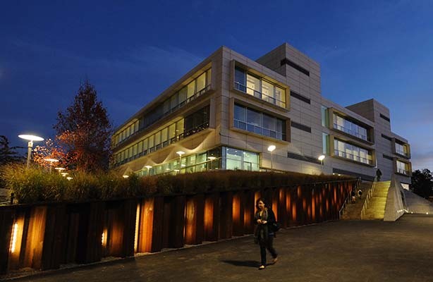A side view of the Spitzer School of Architecture at twilight, with a student walking by.