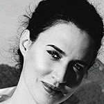 Headshot of Carla Juaçaba, head slightly tilted to the right and smiling at the camera.