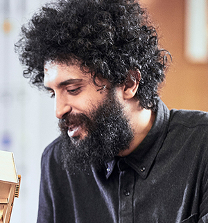 Headshot of Ali Askerinjad, looking down to the left and smiling.