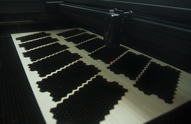 An interior view of the Digital Fabrication Shop at the top-tier Spitzer School of Architecture, featuring a large-bed laser cutter in operation.