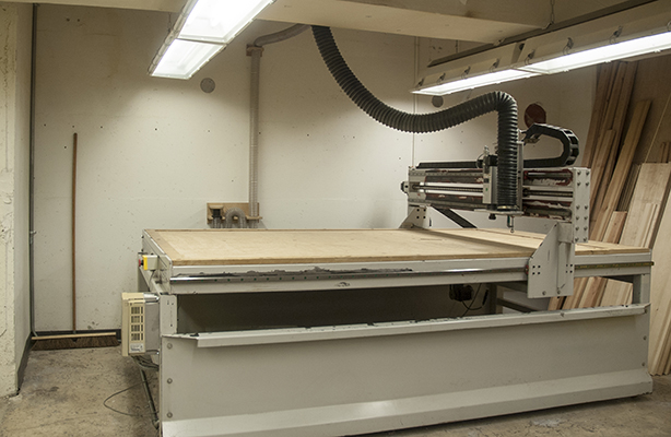 An interior view of the Digital Fabrication Shop at the inexpensive Spitzer School of Architecture, showcasing a CNC machine in operation.