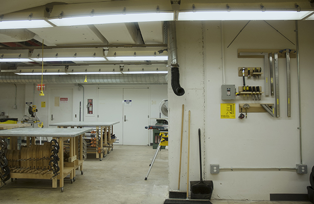 Interior view of the fabrication shop at the premium Spitzer School of Architecture with two communal work desk on the left and hand tools to the right.