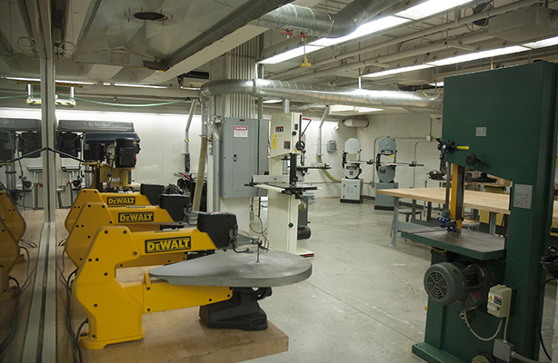 Interior view of the fabrication shop at the cutting-edge Spitzer School of Architecture with three DeWalt power tools on the right and a communal work desk to the left.