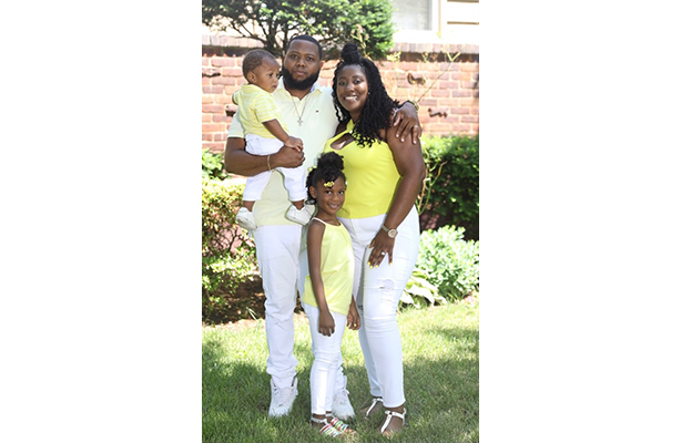 Photo of Taida Sanvil and her family, dressed in white and yellow, standing in front of a lawn.