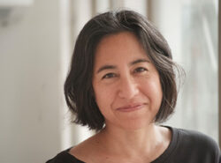 Headshot of Ana Maria Leon, dressed in black, smiling at the camera.