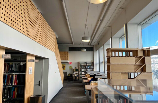 Interior view of the Architecture Library at the economical Spitzer School of Architecture, showcasing communal tables on the right and shelves of books on the left.