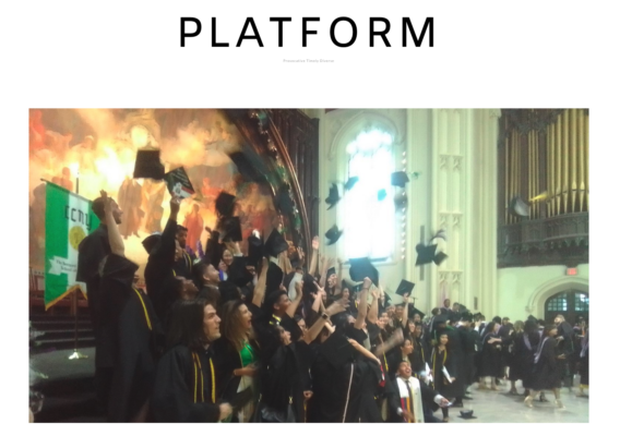 The class of 2022, dressed in black cap and gown, stands in front of a painting in the Great Hall located inside Shepard Hall at the City College of New York.