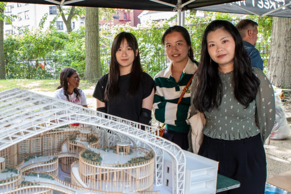 Three B. Arch students from the Spitzer School of Architecture stand behind their architectural model.