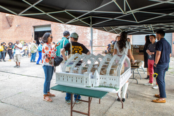 A group of people gathered around an architectural model designed by Spitzer School of Architecture students.