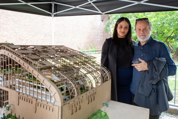 Two individuals stand behind an architectural model designed by Spitzer School of Architecture students.