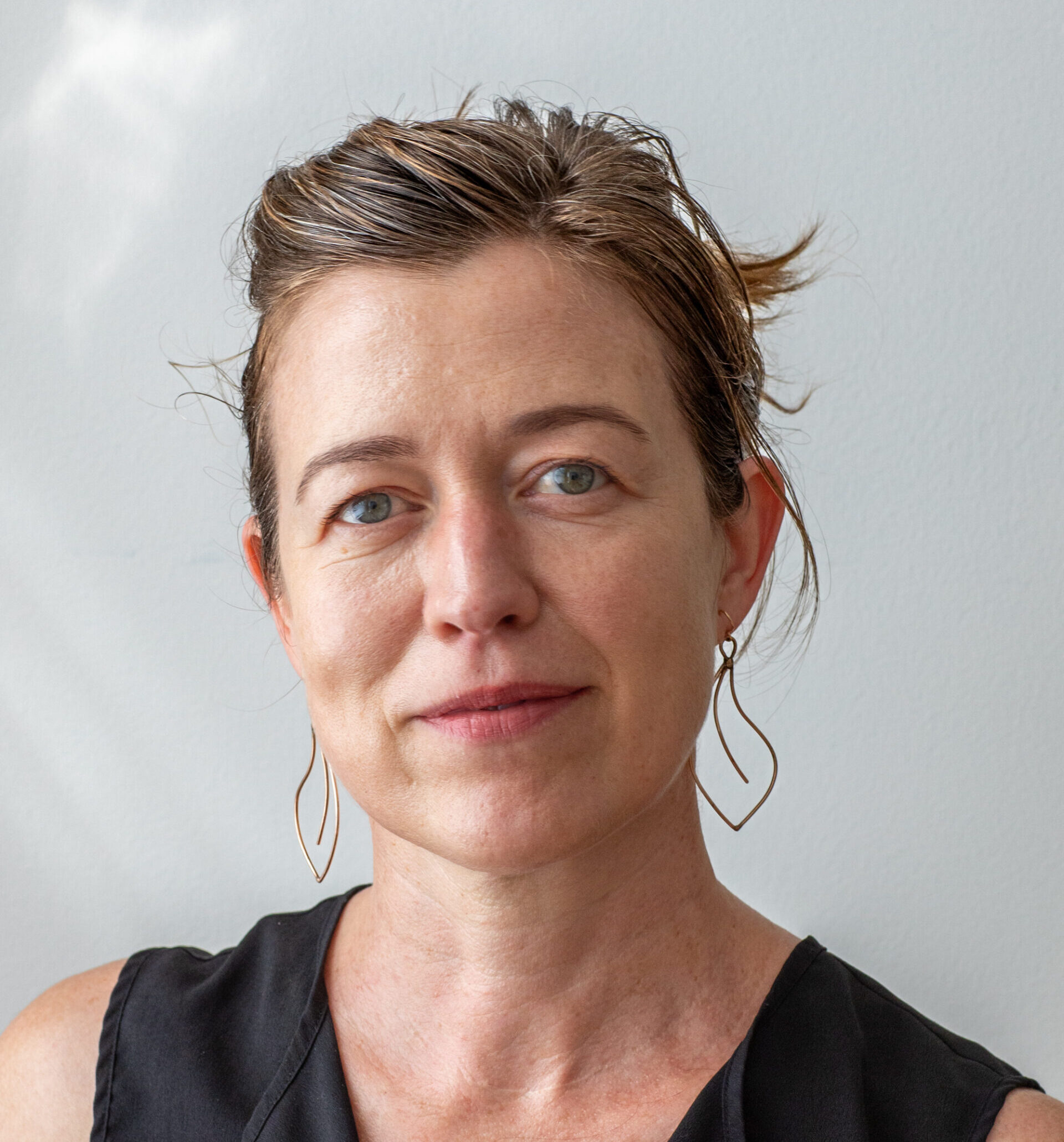 Headshot of Evi Abeler, head slightly tilted to the left and smiling at the camera.