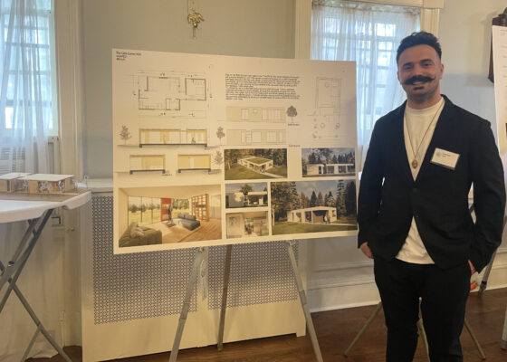 A Bachelor of Architecture student standing in front of his project on an easel.