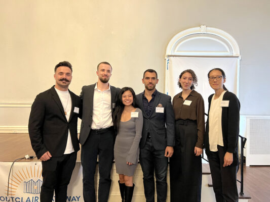 A group of six people, consisting of five B.Arch students and one professor, smiles in a line.