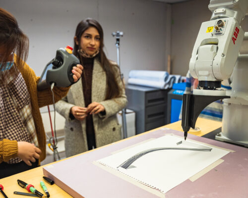 Two MS Arch students programming the ABB robotic arm to draw with a sharpie in the Robotics Lab at the Spitzer School of Architecture.