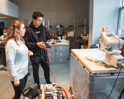 Two Master of Architecture students programming the ABB robotic arm in the Robotics Lab at the affordable yet high-quality Spitzer School of Architecture.