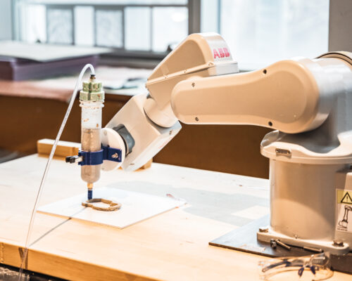 An interior view of the Robotics Lab at the top public architecture school, featuring an ABB robotic arm programmed to 3D print clay.
