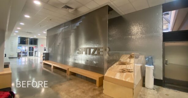 Photograph of a bench in front of a translucent wall in front of a sign that reads 