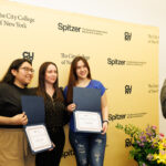 Three individuals stand in front of a Spitzer School of Architecture backdrop, smiling as someone takes a picture.