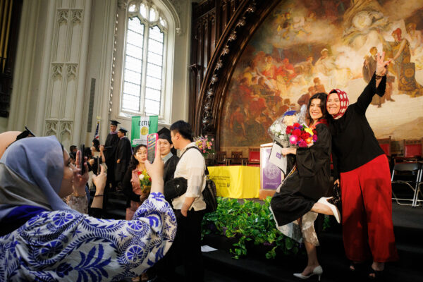 The 2023 graduating class takes pictures in the Great Hall of Shepard Hall at the City College of New York.