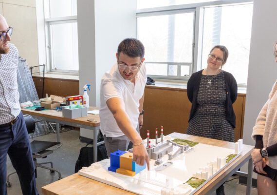A student points to the 3D model while an administrator stands and admires.