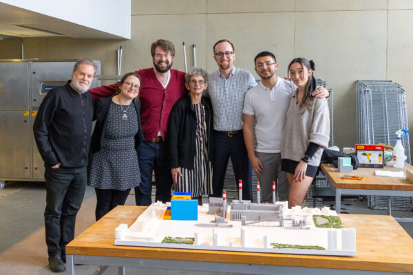 A group poses and smiles behind the 3D model.
