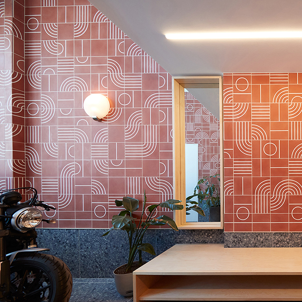 Mirror and lighting fixture hanging on a wallpapered wall.