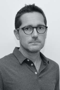 A black-and-white headshot of Martín Cobas, a man with short dark hair and dark-rimmed glasses, wearing a polo shirt and looking directly at the camera with a neutral expression.