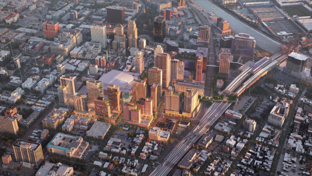 An aerial architectural rendering of a massive urban development project in Newark, New Jersey, centered around the Prudential Center arena. The image displays a dense cluster of modern residential and commercial high-rises with varied facades, many featuring rooftop greenery and terraces. To the right, a large multi-platform transit station is visible with several tracks and a pedestrian bridge. The development is integrated into the existing city grid, with older low-rise buildings and historic structures in the surrounding blocks. In the upper right, the Passaic River and a red lift bridge can be seen under a soft, late-afternoon sky.