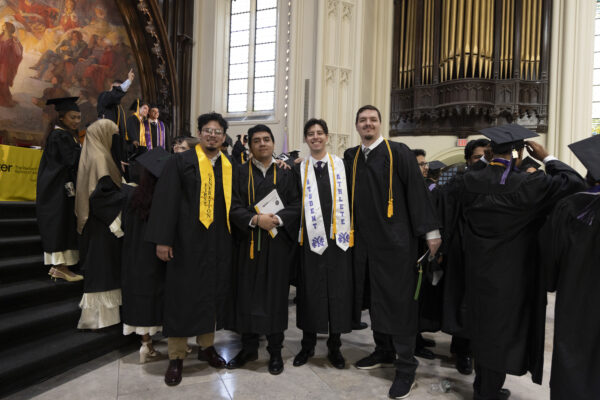 Four graduates smiling for a photo together, featuring 